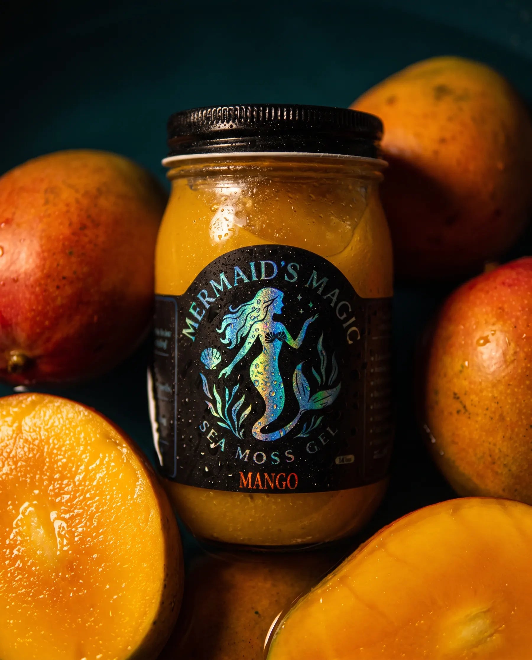 Styled scene: a jar of mango sea moss gel nestled among whole ripe mangoes